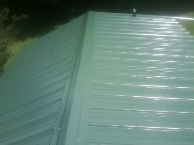 New green metal panels meeting at the ridge of a roof — Flat Roof Repair work by our crew in Live Oak