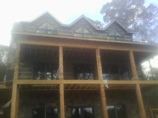 Dormers and porch framing on a large log home under construction — Roof Coating work by our crew in Live Oak