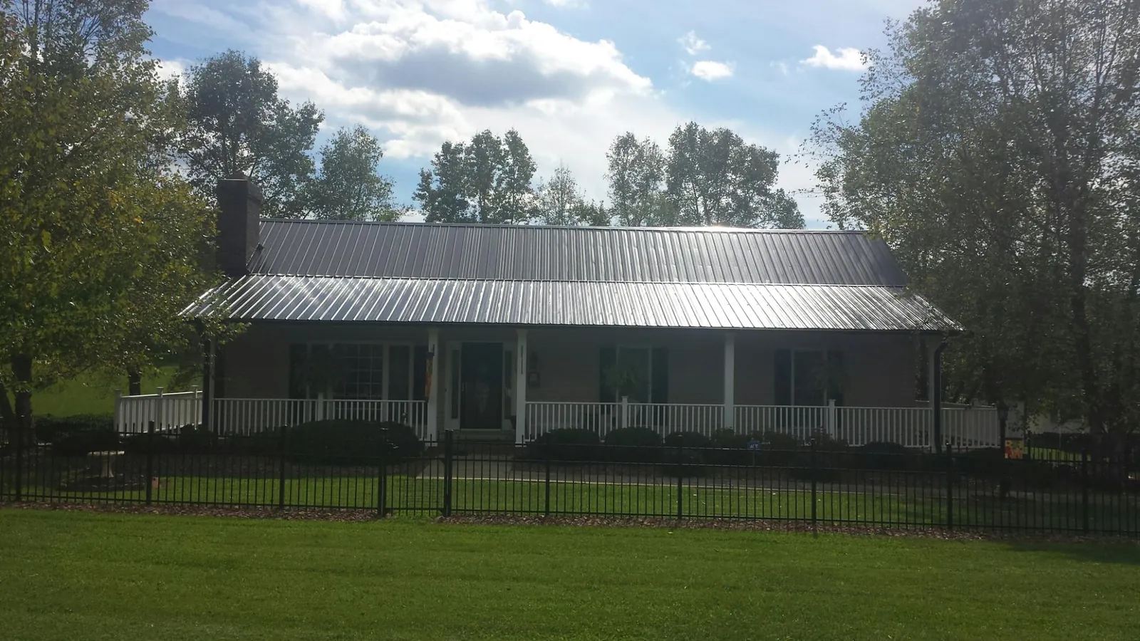 Gray metal roof on a brick ranch with a full width front porch — Gutter Guard Installation work by our crew in Live Oak
