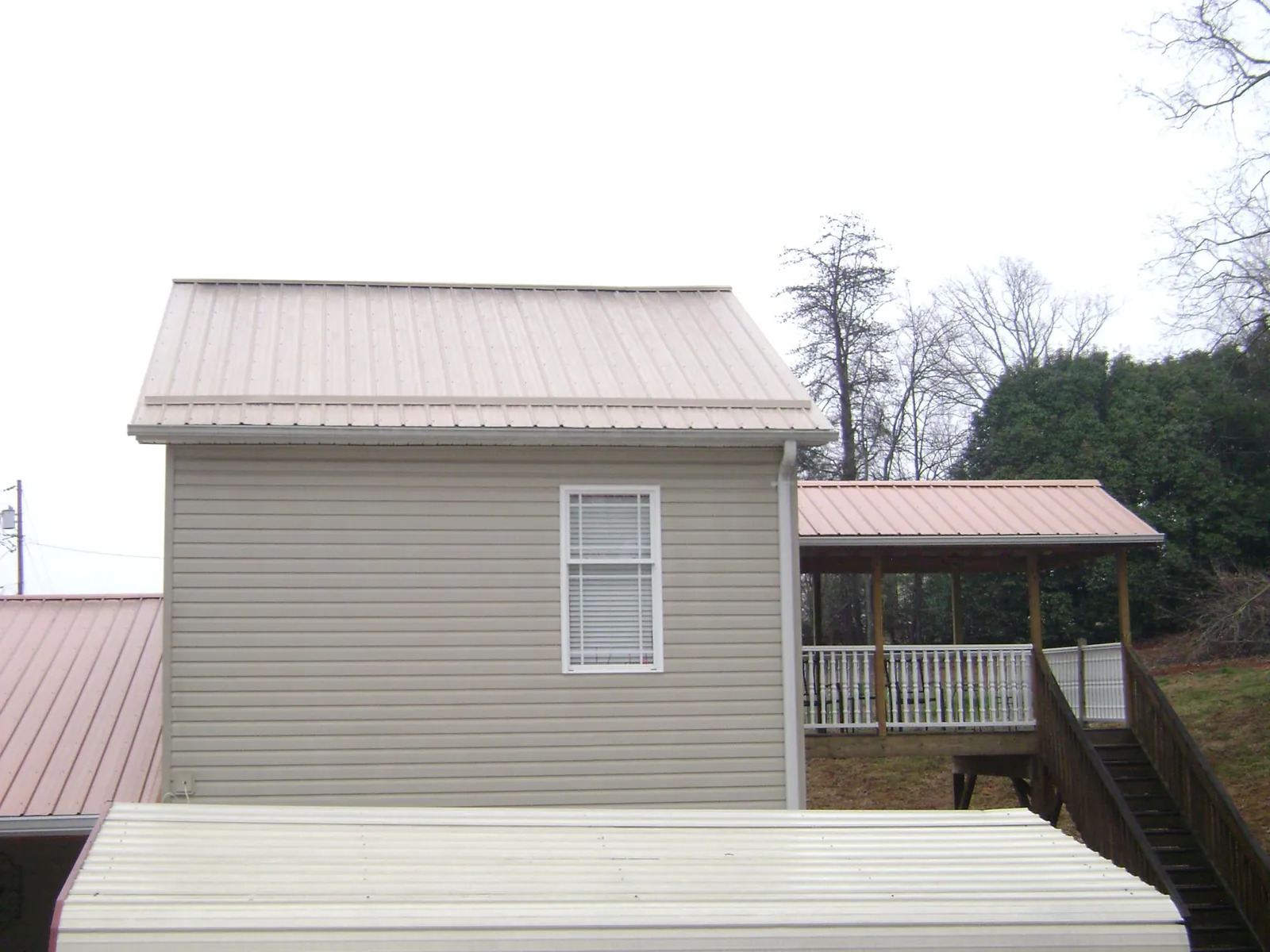 Tan metal roofs on a two story addition and attached porch, from a Roof Replacement job in Live Oak
